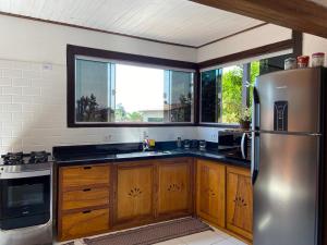 a kitchen with wooden cabinets and a stainless steel refrigerator at Casa no Centro da Ilhabela - Vila - SP in Ilhabela +12 photos
