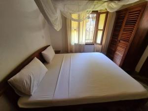 1 dormitorio con 1 cama blanca grande y ventana en Luxury boutique villa with gorgeous pool en Malindi