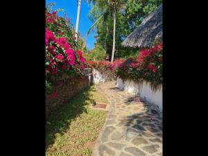 un jardín con flores rosas y un camino de piedra en Luxury boutique villa with gorgeous pool en Malindi