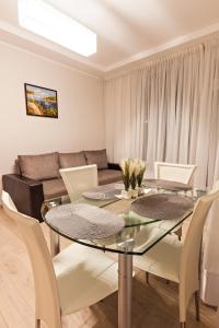 a dining room with a glass table and a couch at Sonia Apartments in Jūrmala