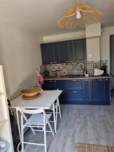 uma cozinha com armários azuis e uma mesa e cadeiras brancas em Appartement VILLERS SUR MER em Villers-sur-Mer