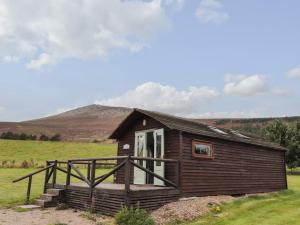 a log cabin in a field with a mountain in the background at Ben View in Keith