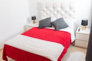 una camera con un letto rosso e bianco con due cuscini di White House ad Arrecife