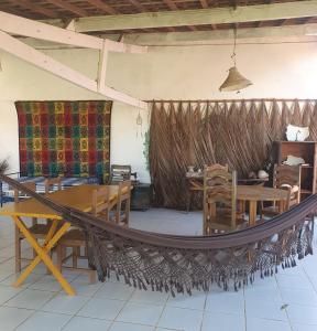 a hammock in a room with tables and chairs at Casarão do Pontal in Coruripe