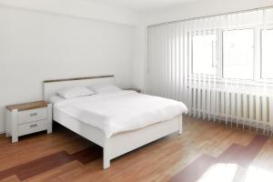 a white bedroom with a white bed and two windows at BTA Apartment Manastur in Cluj-Napoca