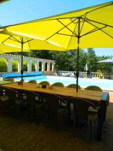 uma longa mesa com guarda-sóis amarelos ao lado de uma piscina em le clos des dryades f em Vers