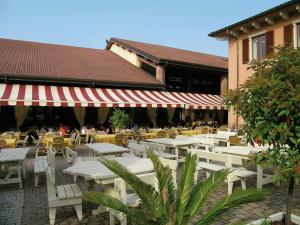 a patio with white tables and chairs and a building at Camping Bella Italia in Peschiera del Garda