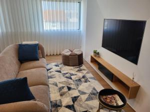 a living room with a couch and a flat screen tv at Apartamento Cinema para férias em Esposende in Esposende