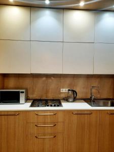 a kitchen with white cabinets and a stove and a microwave at Apartament - Axis palace saburtalo in Tbilisi City