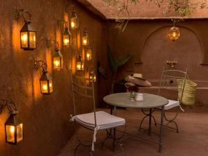 einen Tisch und Stühle in einem Zimmer mit Beleuchtung in der Unterkunft CASA ABRACADABRA in Marrakesch