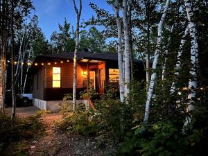 uma pequena cabana na floresta com luzes acesas em L'Escale de la Martine - Intimité, SPA et boisé em Petite-Rivière-Saint-François