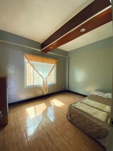 an empty bedroom with a bed and a window at Bilman's Transient House in Baguio