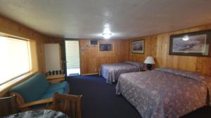 une chambre d'hôtel avec deux lits et une chaise dans l'établissement Westwood Motel, à West Yellowstone