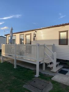 a white mobile home with a porch and a deck at Victory Coaster in Seasalter