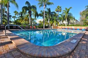 a swimming pool with palm trees in the background at The Capri at Siesta in Siesta Key