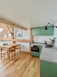 a kitchen with green cabinets and a wooden table at Triplex In The Heart Of Chamonix in Chamonix-Mont-Blanc