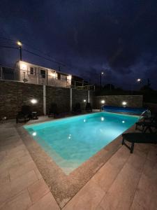a swimming pool at night with a house in the background at Fonte Retreat - Holiday Home in Sandim
