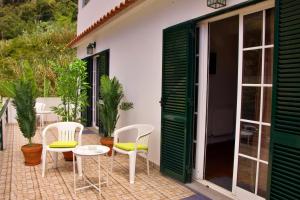 a patio with white chairs and a table at Ivone Madeira Guest House in Funchal