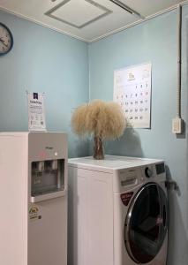 eine Waschküche mit einer Waschmaschine und einer Uhr in der Unterkunft Jo Eun Jip Guesthouse in Mokpo