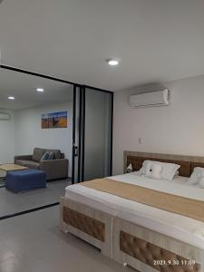 um quarto com uma cama grande e um sofá em Berilo Deluxe Apartahotel em Barranquilla