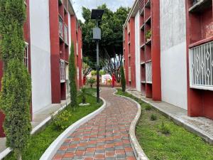 a brick path between two red and white buildings at Sensity Home Dpto céntrico hermoso y cómodo in Tehuacán