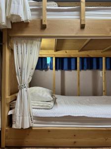 a bunk bed with white sheets and a curtain at Jo Eun Jip Guesthouse in Mokpo