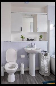 a white bathroom with a toilet and a sink at Marston 5 Bedroom Home With Parking Near NEC & BHX in Marston Green +28 photos