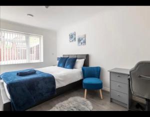 a bedroom with a bed and a blue chair at Marston 5 Bedroom Home With Parking Near NEC & BHX in Marston Green