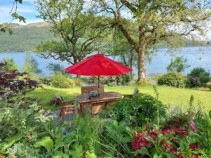 a picnic table with a red umbrella in a garden at the waterside - carrick castle - loch goil in Carrick