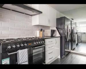 a kitchen with a black stove and a refrigerator at Marston 5 Bedroom Home With Parking Near NEC & BHX in Marston Green