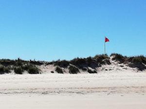 a red flag on top of a sandy beach at TY MERVENT, l'océan à 500 m in Saint-Jean-Trolimon