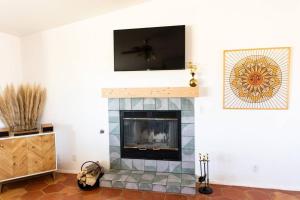 a living room with a fireplace with a flat screen tv at Sun Runner - Serene desert home w/pool & hot tub in Twentynine Palms
