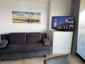 uma sala de estar com um sofá e uma televisão de ecrã plano em Hotelturm Apartment em Augsburg