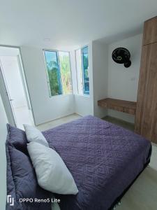 1 dormitorio con 1 cama de color púrpura y 2 ventanas en Casa vacacional condominio bambú, en Carmen de Apicalá