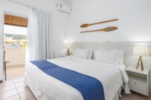 um quarto com uma cama branca e um cobertor azul em Makkai Resort Bombinhas em Bombinhas