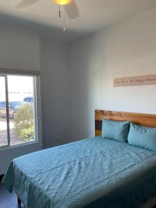 1 dormitorio con 1 cama con edredón azul y ventana en Caracoles Homes en Puerto Peñasco
