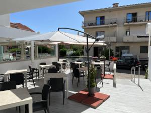 un patio con mesas, sillas y una sombrilla en Hotel Sandalion en Santa Teresa Gallura