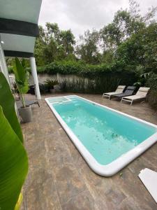 una gran piscina en un patio con 2 sillas en Foresthouse, en Florianópolis