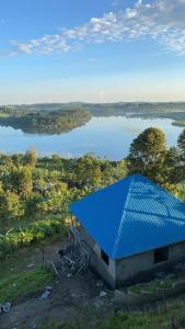 a building with a blue roof next to a lake at Saka Laka in Fort Portal