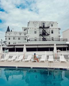 un niño sentado en una cornisa junto a una piscina frente a un edificio en The Inn Of Cape May, en Cape May