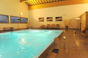 a large swimming pool with chairs in a building at Appartements montagne, piscine et sauna in Orelle