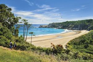 two people walking along a beach with the ocean at Room in Lodge - Pension Oria Luarca Asturias in Luarca