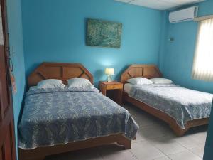 two beds in a room with blue walls at Vista Mar Hotel  in Bocas Town