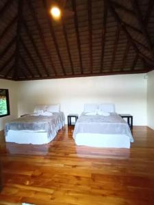 two beds in a bedroom with a wooden floor at Cascadas Corcovado - luxury villa in Charcos