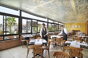 two men standing in a restaurant with tables and chairs at Hotel Gran Palace in Santiago
