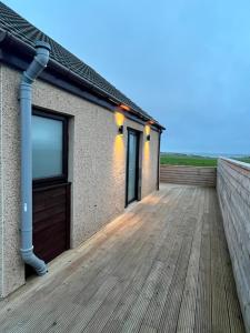 un paseo marítimo de madera que conduce a una casa con techo en Loanside Lodge, Self-Catering, Holm, Orkney. en Saint Marys