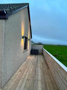 a balcony of a house with a wooden deck at Loanside Lodge, Self-Catering, Holm, Orkney. in Saint Marys