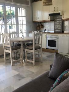 a kitchen with a table and chairs and a couch at Calma La Barrosa Apartamento in Chiclana de la Frontera