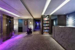 台北市にあるHotels Here - Taipeiの紫色の照明を用いた廊下に座る者