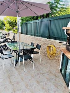 um pátio com uma mesa, cadeiras e um guarda-sol em Vivenda para férias (Algarve) na Manta Rota
